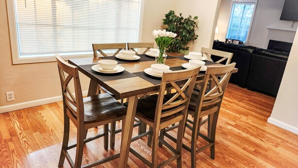 Comedor con mesa de madera dispuesta para cuatro personas, rodeada de sillas de madera.