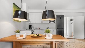 A modern kitchen with two pendant lights, a wooden dining table, and a stainless steel refrigerator.