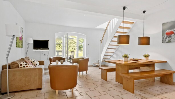 A modern living room with a sofa, chairs, a wooden dining table, and a staircase. - Amazing apartment in Nimtofte with WiFi (Nimtofte)
