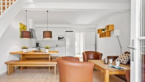 A modern living room with a wooden dining table, leather chairs, a sofa, and a kitchen in the background. - Amazing apartment in Nimtofte with WiFi (Nimtofte)