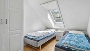 A small, well-lit attic bedroom with a skylight, two beds, and a white wardrobe. - Stunning apartment in Nimtofte with WiFi (Nimtofte)