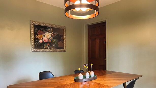A dining area with a large wooden table, black chairs, and a decorative centerpiece. - Family-friendly home, beautiful fenced-in yard, short walk to Ball State Campus (Muncie)