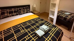 Ein Schlafzimmer mit Bett, Nachttisch, Lampe und Kleiderschrank.