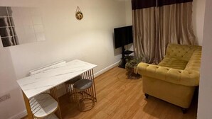 Ein Wohnzimmer mit einem Marmortisch, einem gelben Sofa, einem Fernseher und einer kleinen Pflanze.