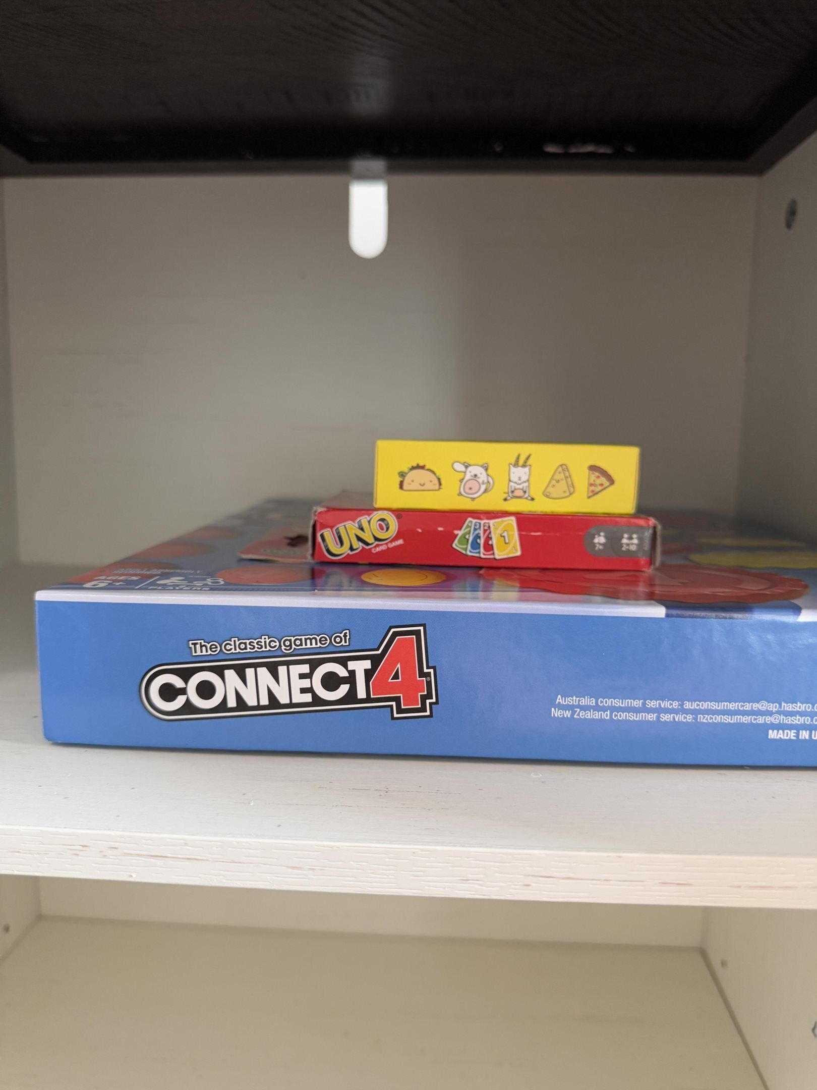 Une boîte de jeu Connect 4 avec des jeux de cartes UNO et UNO Kids placés sur le dessus.