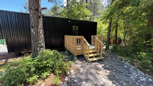 Un chalet rustique doté d’une terrasse en bois et d’un sentier en pierre menant à un escalier en bois.