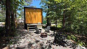Un espace extérieur rustique aménagé avec une table et des chaises en bois, un foyer en pierre et une terrasse en bois.