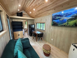 Un espacio habitable compacto con sofá, mesa de comedor y un amplio ventanal con vistas a un paisaje pintoresco.