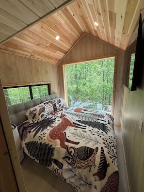 Un dormitorio con una cama grande, una ventana y techo de madera.