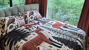 Une chambre avec un grand lit, une fenêtre avec des rideaux et une vue sur une forêt.