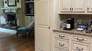 A kitchen with white cabinets, a coffee maker, and a stone fireplace. - Spacious 4 Bed 3 Bath Auburn Game Day Home (Auburn)