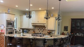 A spacious kitchen with a central island, bar stools, and a chandelier. - Spacious 4 Bed 3 Bath Auburn Game Day Home (Auburn)