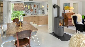 A modern kitchen with wooden cabinets, a dining table with chairs, a built-in stove, and a large window with a view of greenery. - 4 bedroom nice home in Gilleleje (Gilleleje)