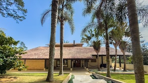A building with a tiled roof, surrounded by palm trees and a well-maintained lawn.