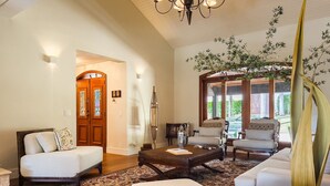 A spacious living room with a large window, a sofa set, a coffee table, and a decorative plant.