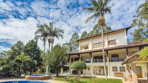 A two-story house with a swimming pool, palm trees, and a well-maintained lawn.
