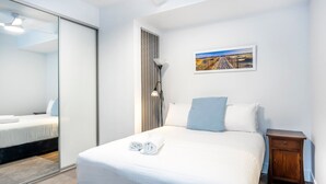 A hotel room with a bed, a nightstand, a lamp, a painting, and a sliding door. - Scarborough Pearl Apartment (Scarborough)