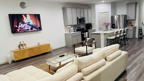 Een moderne woonkamer met een beige bank, een glazen salontafel en een televisie waarop een haard wordt getoond.