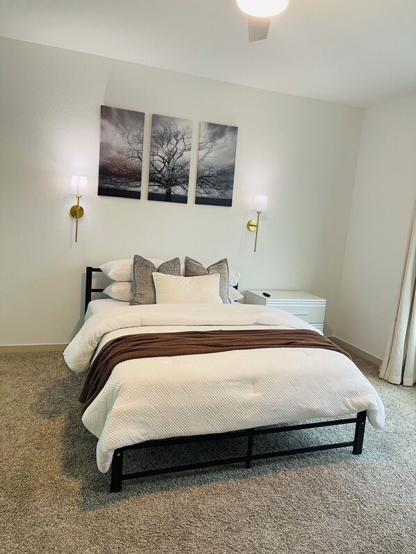 Ein Schlafzimmer mit einem Bett, zwei Wandleuchten, einem Nachttisch und einem Kunstwerk über dem Bett.
