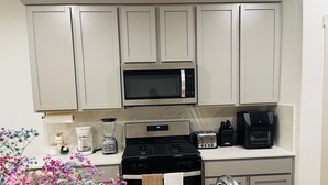 Een moderne keuken met een magnetron, broodrooster, koffiezetapparaat en een fornuis.