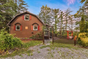 A wooden house with a porch, surrounded by trees and a gravel path. - Lookout Point - Firepit, Pickle Ball, Balcony, Pet (Sevierville)
