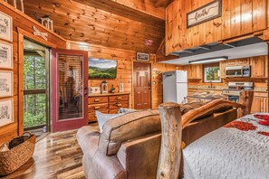A cabin interior with a wooden interior, a kitchen with modern appliances, a large window, and a cozy seating area. - Lookout Point - Firepit, Pickle Ball, Balcony, Pet (Sevierville)