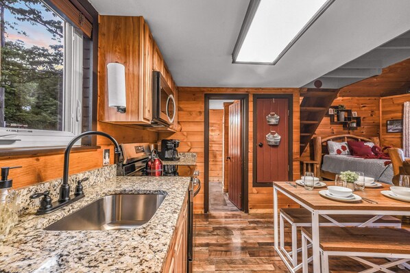 A compact kitchen with a granite countertop, stainless steel sink, and wooden cabinetry. - Lookout Point - Firepit, Pickle Ball, Balcony, Pet (Sevierville)