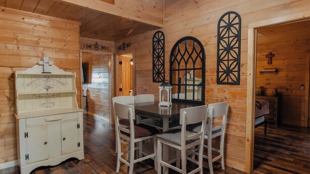 Un intérieur en bois comprenant une table à manger, des chaises, un buffet et des motifs décoratifs sur les fenêtres.