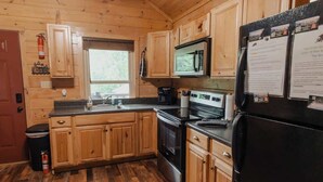 Une cuisine rustique, située dans une cabane en bois, équipée d’une cuisinière, d’un four, d’un four à micro-ondes et d’un réfrigérateur.