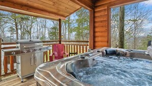 Une terrasse en bois avec un jacuzzi, un barbecue et un espace salon.