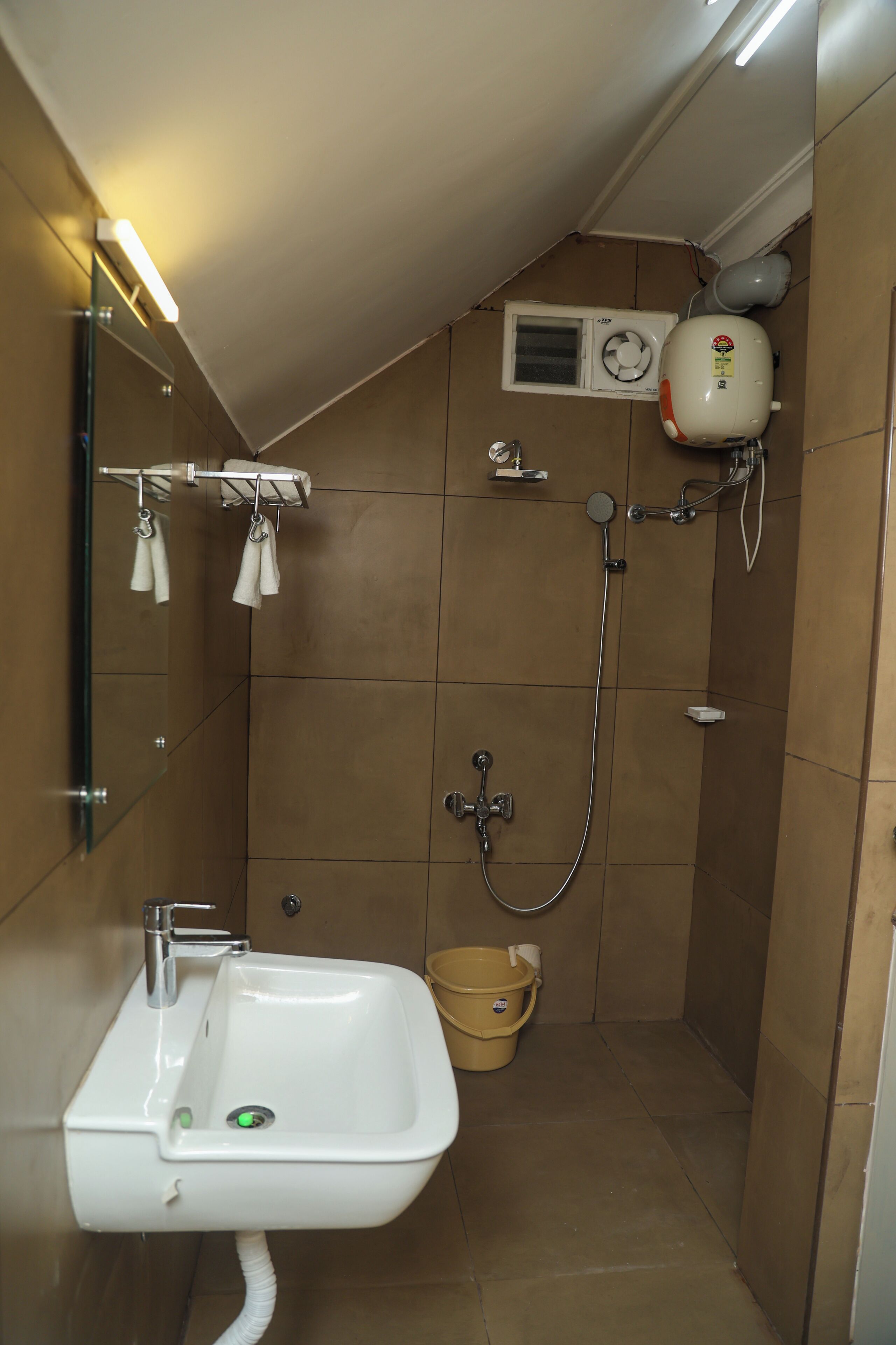 A small, tiled bathroom with a sink, a shower, and a toilet.
