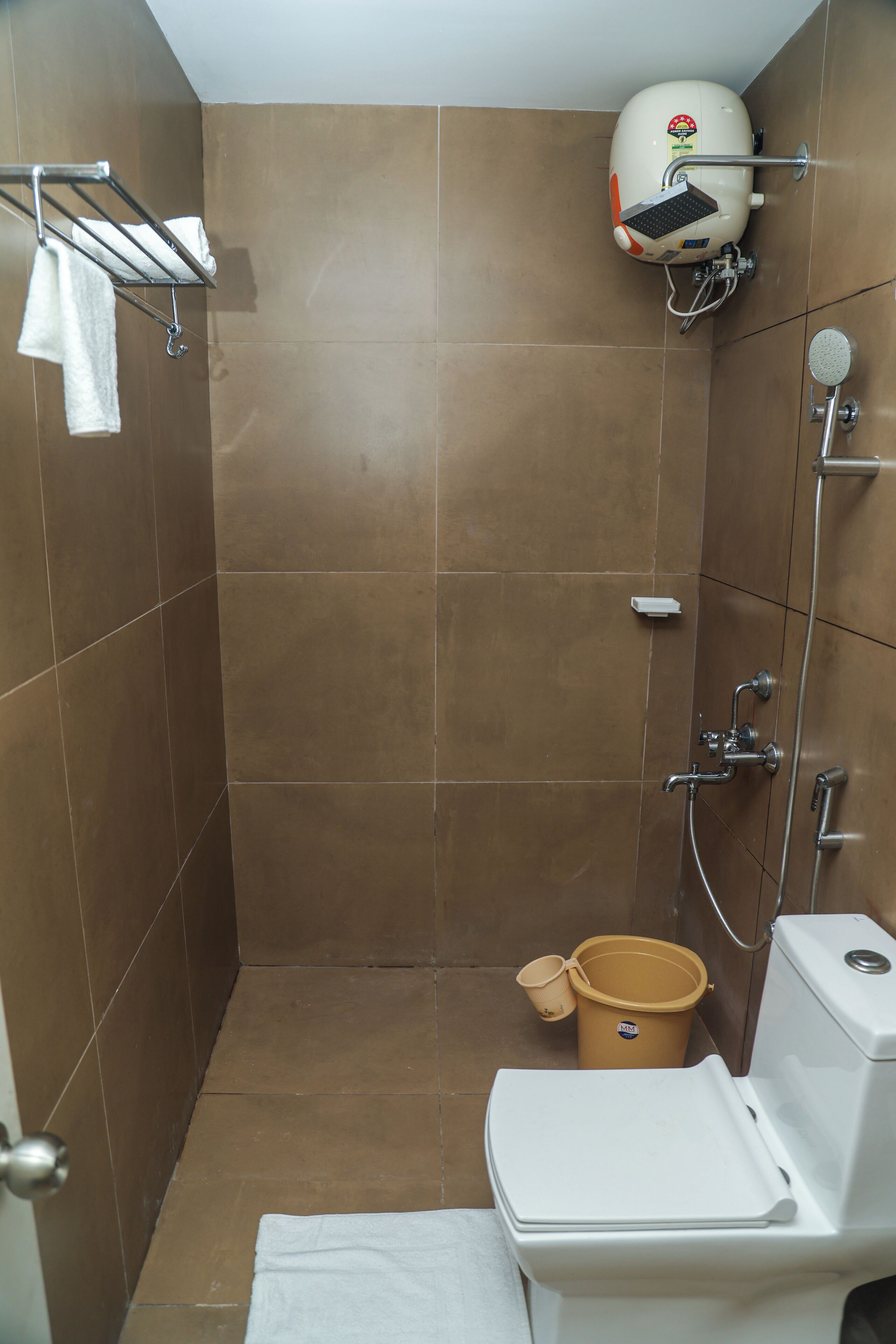 A bathroom with a shower, toilet, and a towel rack.