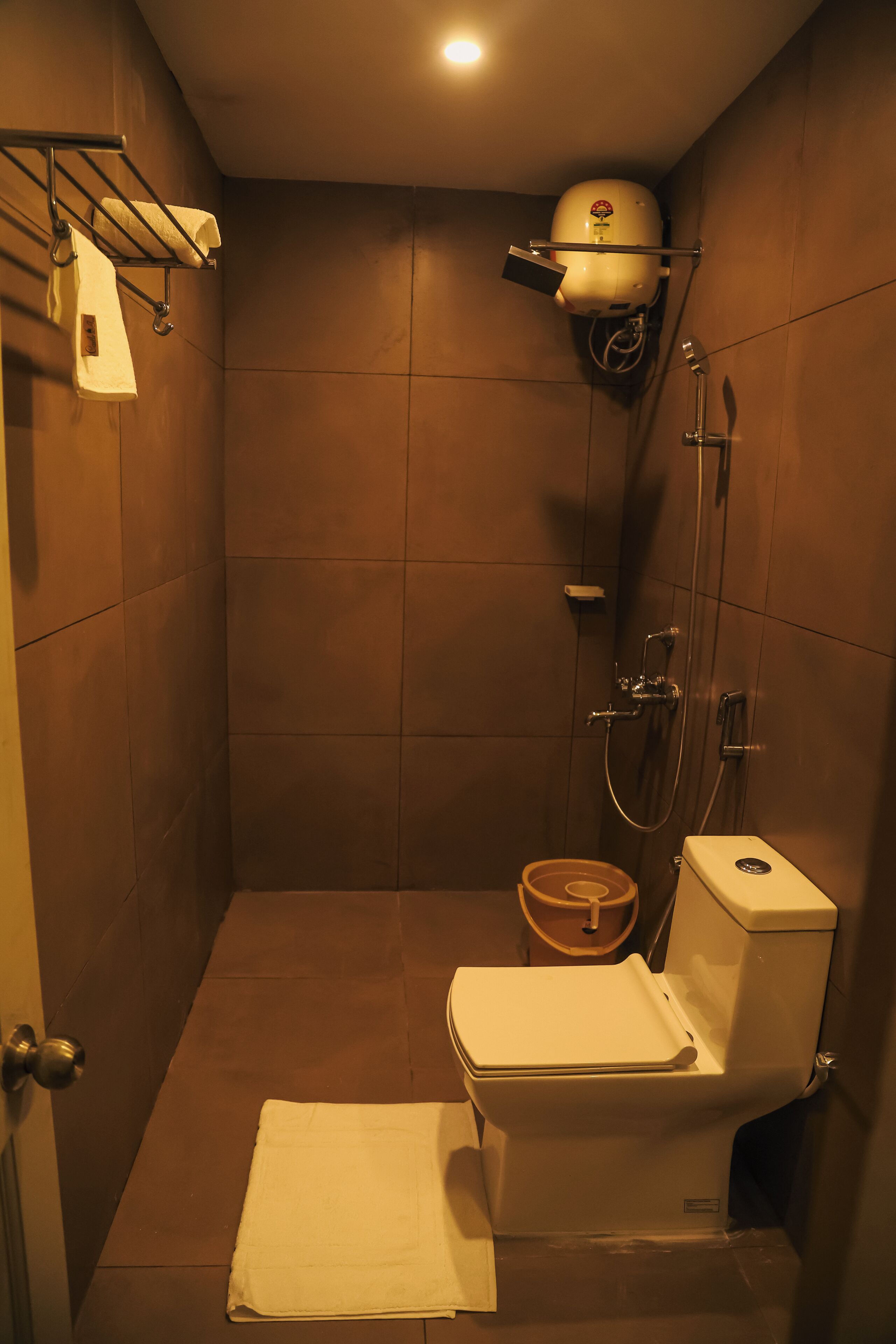 A compact shower stall with a toilet and a towel rack.