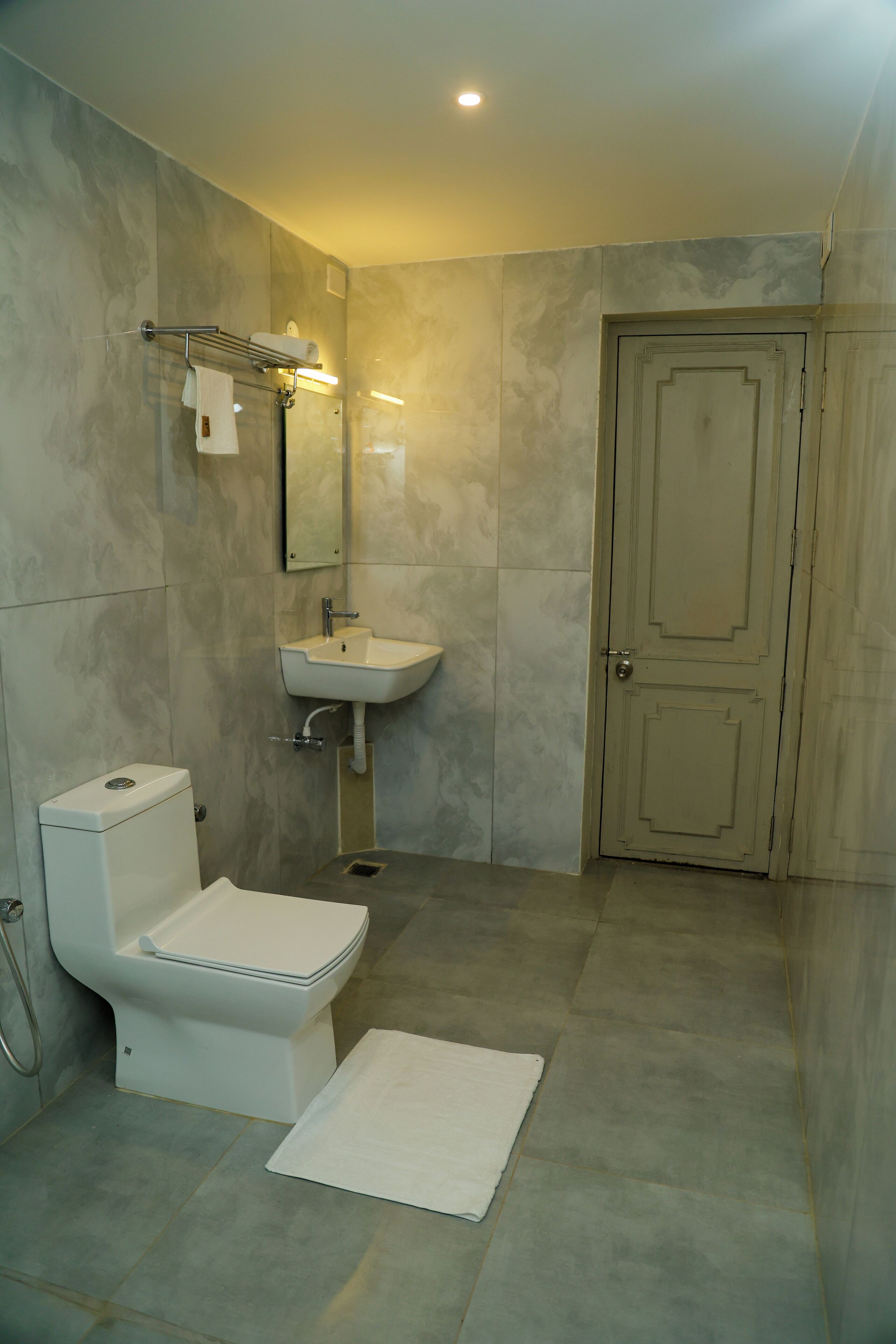 A bathroom with a toilet, sink, and mirror.