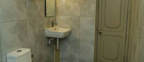 A bathroom with a toilet, sink, and mirror.