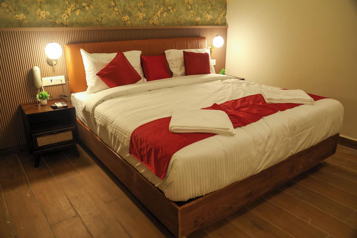 A neatly made bed with white and red bedding, a wooden headboard, and bedside lamps.
