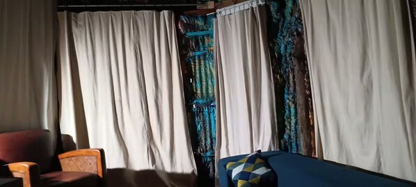 Una habitación con sofá, sillón y cortinas.