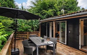 An outdoor deck with a table and chairs, a wooden fence, and a sliding glass door leading to a cabin.