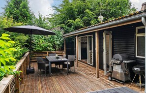 A wooden deck with a table and chairs, a grill, and a covered area with an umbrella.