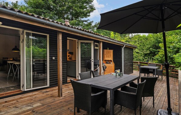 A wooden deck with a table and chairs, a grill, and a wooden cabinet.