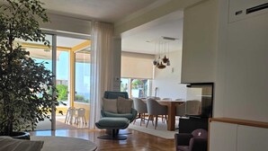Een moderne woonkamer met een bank, een ronde salontafel en een eethoek met tafel en stoelen.
