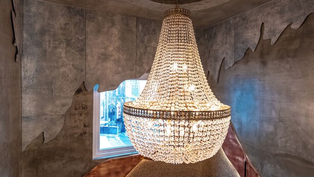 A chandelier in a room with a unique architectural design, including a curved ceiling and a window providing a view. - Hi Seodaemun (Seoul)