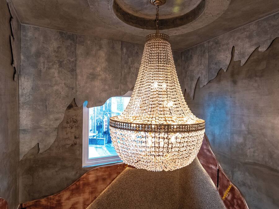 Un candelabro en una habitación con un diseño arquitectónico singular, que incluye un techo curvo y un ventanal.