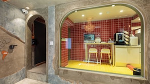 A room with a red-tiled wall, a yellow floor, a small table with a chair, a television, and a decorative chandelier. - Hi Seodaemun (Seoul)