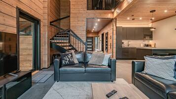 Un interior moderno con una escalera de madera, sofás de cuero y una zona de cocina.