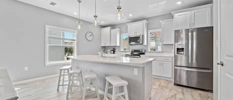 A modern kitchen with white cabinets, stainless steel appliances, and a central island with stools.
