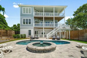 A two-story house with a pool, outdoor seating, and a covered patio.