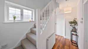 A modern staircase with a white railing, a radiator, and a potted plant on the landing.