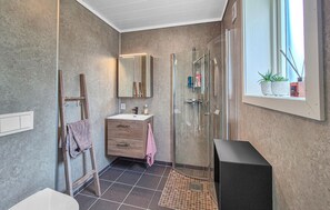 A modern bathroom with a glass shower, a vanity with a mirror, and a window with plants. - 5 bedroom gorgeous home in Bremnes (Bremnes)