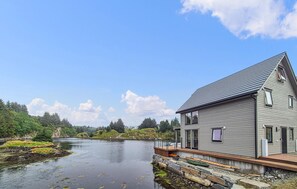 A house by a lake with a dock, surrounded by trees and a clear sky. - 5 bedroom gorgeous home in Bremnes (Bremnes)
